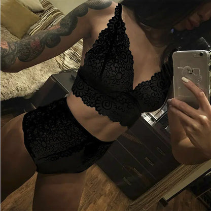 Person wearing a black lace bra and panties set, taking a photo with a smartphone.