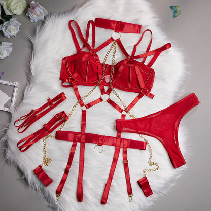 Red lingerie set with gold chains on a white fur surface.