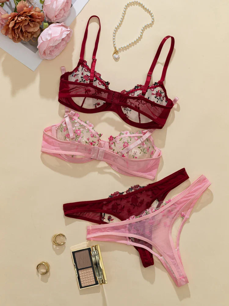 Set of pink and red lingerie with floral details on a beige background.