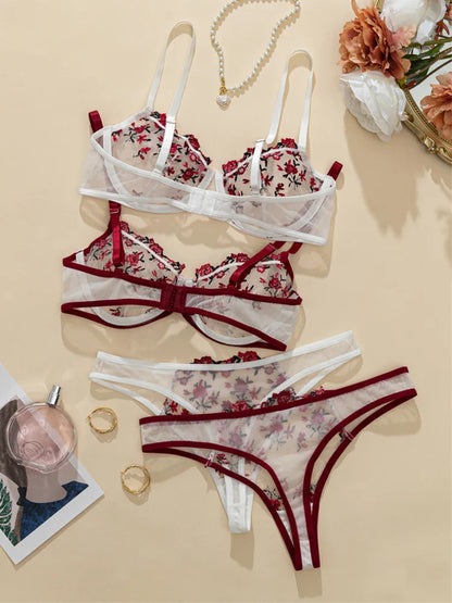 Floral lingerie set with bra, panties, and thong on a beige surface.