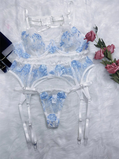Blue floral lingerie set on a textured white surface with flowers.
