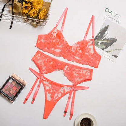 Coral lace lingerie set on a white surface with makeup and coffee.