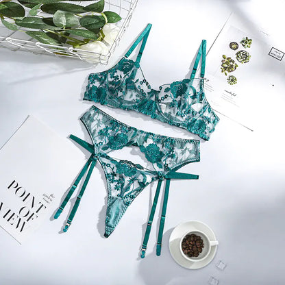 Green floral lingerie set on a white surface with a cup of coffee and greenery.
