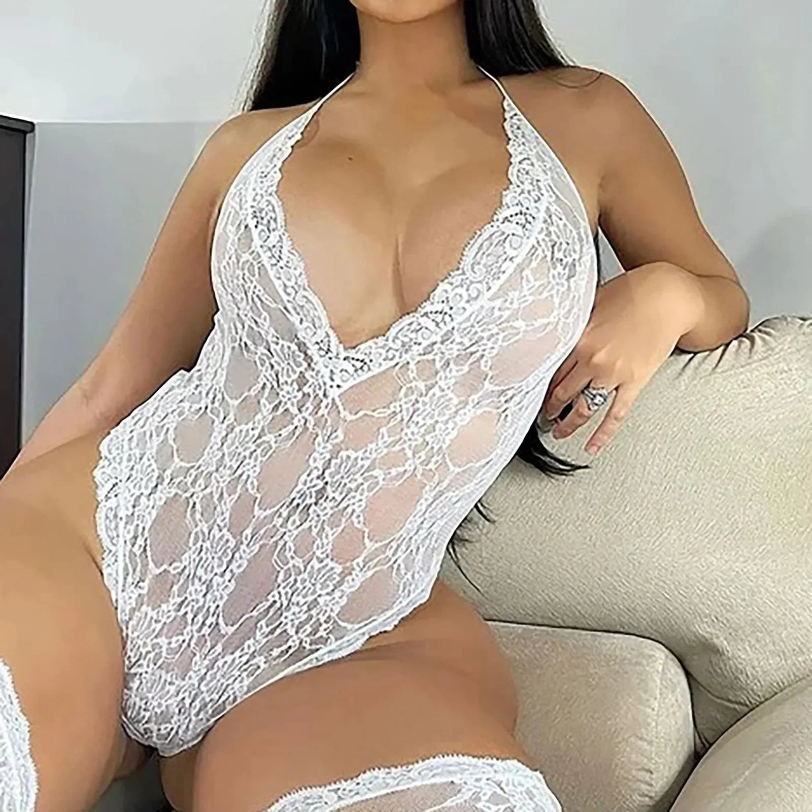 Person wearing a white lace lingerie set sitting on a couch.