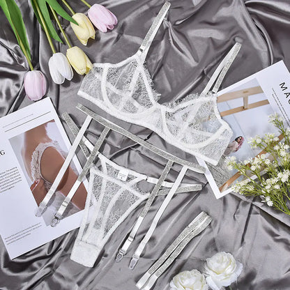 Set of lace lingerie on a satin surface with flowers and magazines.