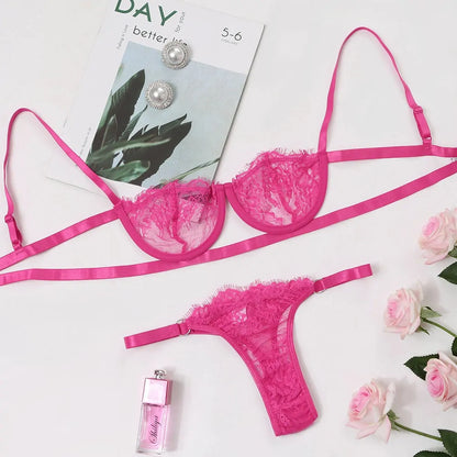 Pink lace lingerie set with earrings and perfume bottle on a magazine and floral background