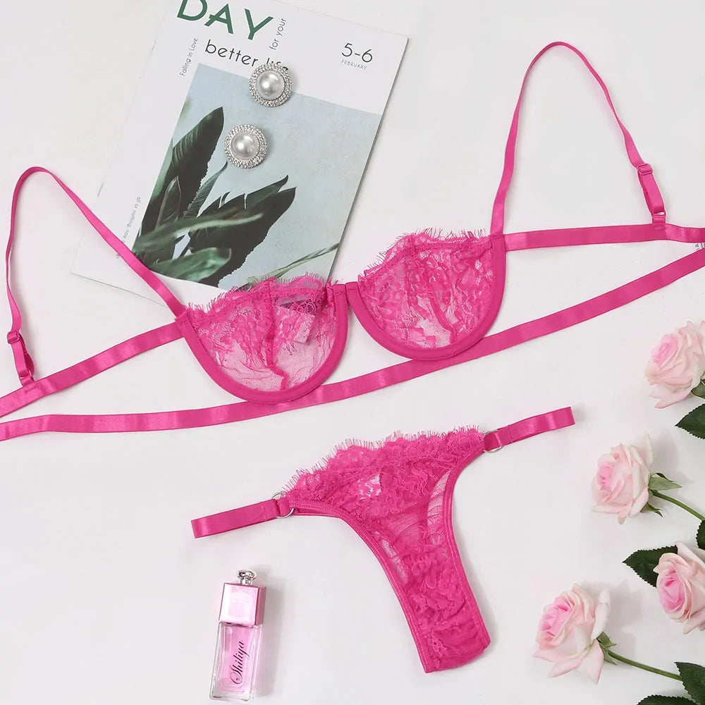 Pink lace lingerie set with earrings and perfume bottle on a magazine and floral background