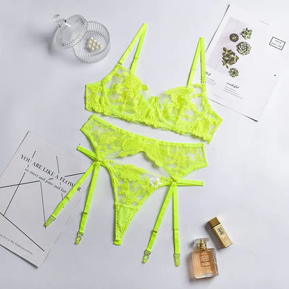 Neon yellow lace lingerie set on a light gray background with a small bottle and decorative items.