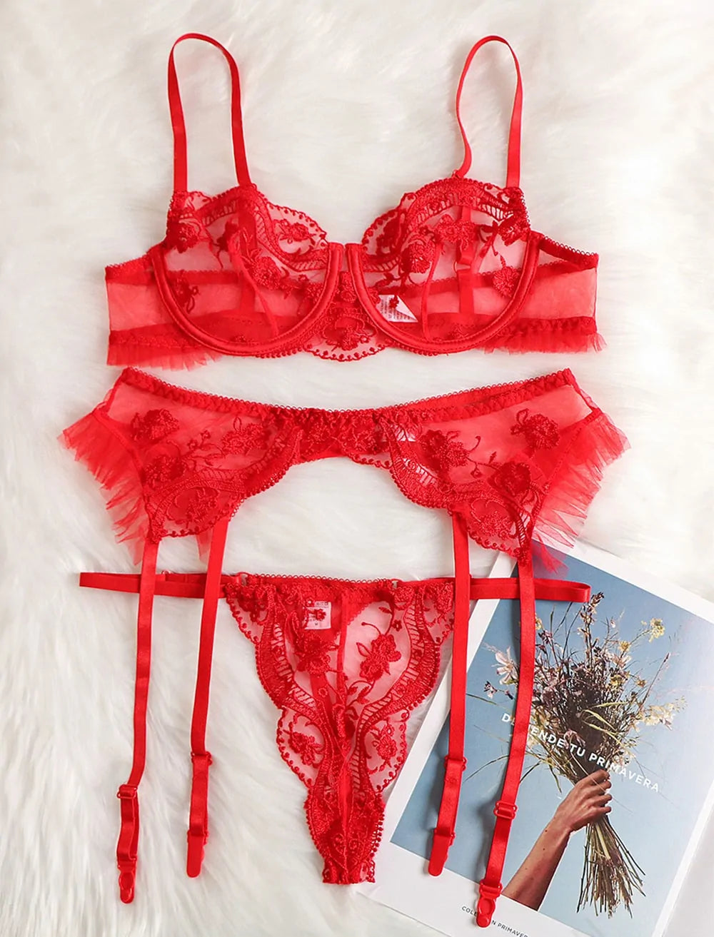 Red lace lingerie set on a textured surface with a magazine in the background.